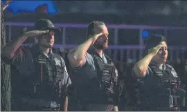  ?? TYLER LARIVIERE — CHICAGO SUN-TIMES VIA AP ?? Chicago police officers salute as a procession for a police officer who was shot and killed earlier during a traffic stop drives by the Cook County Medical Examiners Office on Sunday. Three people are in custody, and police say a gun was recovered.