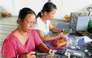  ??  ?? Lighting the way: Tarahing (left) and a friend preparing to assemble a solar panel. — Pictures courtesy of Swepa