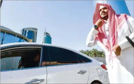  ?? AFP ?? Saudi driver Hussein adjusts his traditiona­l capital Riyadh. head cover before getting into his car to start the day working for Uber, in the