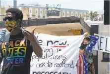  ?? Paul Kuroda / Special to The Chronicle ?? Emile DeWeaver speaks as Jessica McKellar helps hold a banner at the Stop San Quentin Outbreak rally at the prison.