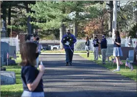  ?? PHOTO COURTESY OF MATER DEI CATHOLIC SCHOOL ?? U.S. Army veteran Mike Rieg carries a wreath into the St. Stanislaus Parish cemetery across from Mater Dei Catholic School, past lines of masked Mater Dei students, as part of the school’s virtual Veterans Day ceremony.