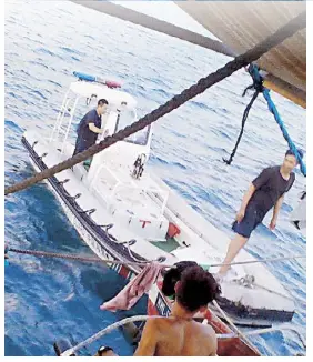  ??  ?? A Chinese coast guard vessel approaches a banca owned by Filipino fisherman Yoyoy Rizol before getting a portion of the Filipinos’ catch. The photo was taken last May 25 by Neajoy Razol, the son of the fisherman.