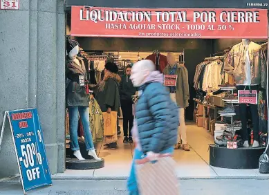  ?? Foto afp ?? ECONOMÍA. Un hombre cruza por una tienda de Buenos Aires que está liquidando sus productos.