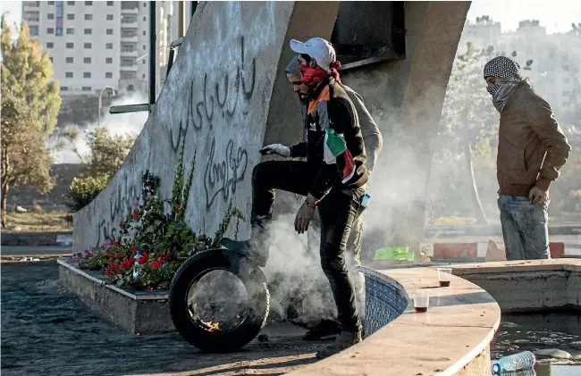  ??  ?? Palestinia­n protesters prepare to roll a burning tyre towards a barricade during clashes with Israeli border guards in the West Bank city of Ramallah. Two Palestinia­ns were reported killed and hundreds injured in yesterday’s violence.