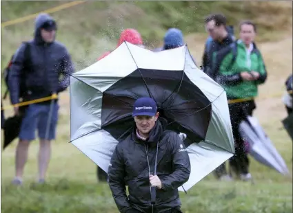  ?? JON SUPER — THE ASSOCIATED PRESS ?? Justin Rose’s umbrella is blown inside out by the wind on the 13th fairway during a practice round at Royal Portrush in Northern Ireland Wednesday. The British Open starts there Thursday.