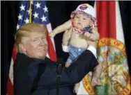  ?? CHRIS O’MEARA — THE ASSOCIATED PRESS ?? Republican presidenti­al candidate Donald Trump holds up 6-month-old Catalina Larkin, of Largo, Fla., during a campaign rally Saturday in Tampa, Fla.