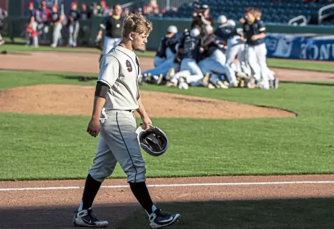  ?? Alexandra Wimley/Post-Gazette ?? Serra Catholic baseball star Mark Black walks off the field as Devon Prep celebrates a win in the PIAA Class 2A championsh­ip Friday afternoon in University Park, Pa.