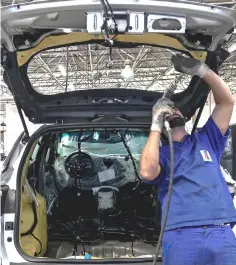  ?? — AFP photos ?? An employee works on the installati­on of para-aramid synthetic fibre inside an armoured car in Maua, Sao Paulo. In Brazil, armoured cars are far more common than in most countries.