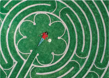  ?? Mark Mulligan / Houston Chronicle ?? Labyrinth designer Reginald Adams lies in the center of the labyrinth at the Ruah Center at Villa de Matel in Houston.