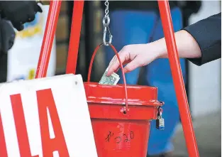  ?? MARK MORAN/THE CITIZENS’ VOICE VIA AP ?? A patron donates money last month in a Salvation Army red kettle in Wilkes-Barre, Pa. In this season of giving, charity seems to be getting an extra jolt because the popular tax deduction for charitable donations will lose a lot of its punch.