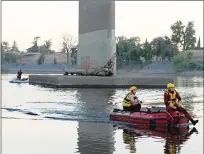  ?? Appeal-Democrat ?? Yuba City Fire Department personnel search the Feather River for a drowning victim near the 10th Street bridge on Friday night.