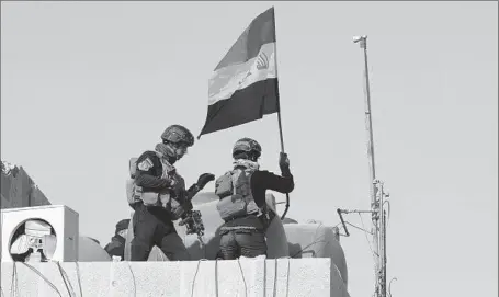  ?? Ahmad al-Rubaye AFP/Getty Images ?? IRAQI anti-terrorism troops hoist the national f lag atop the key government complex in Ramadi, a long-contested city. The victory was a morale booster, but defense experts caution that it is too soon to speak of a turning point in the struggle against...