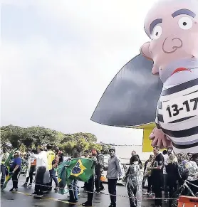  ??  ?? In this May 10, 2017 AP photo, demonstrat­ors stand near a large inflata table doll depicting former President Luiz Inácio Lula da Silva in prison garb in Curitiba, Brazil. Lula appears bound for prison after a ruling agaainst him by Brazil’s top court on Thursday, April 5.