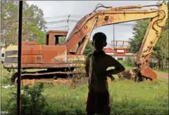  ?? PHA LINA ?? A boy stands in front of a burnt out excavator in Phnom Penh’s Russey Keo district earlier this week after it was destroyed in 2013.