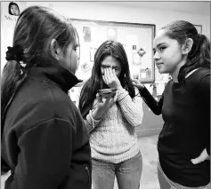  ?? — AFP photo ?? Jocelyn (centre) reacts while speaking wth her father by phone as sisters Fatima (right) and Yuleni (left) listen nearby on campus after school in Los Angeles, California.