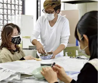  ?? ?? Lacquer artist Yuzo Eto, center, teaches kintsugi to students in Kobe.