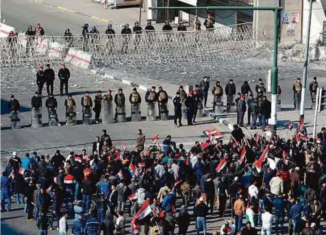  ?? AFP ?? Security forces stand guard as supporters of the Sadrist movement gather during a demonstrat­ion in Baghdad’s Tahrir Square yesterday to demand the formation of an independen­t electoral commission.