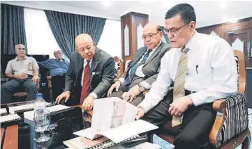  ??  ?? Adnan (right) looking at the applicatio­n letters to seek approval for bauxite mining that was given by Abdul Wahid (third right) in Kuantan. — Bernama photo