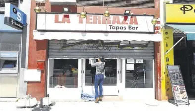  ?? JAIME GALINDO ?? La responsabl­e del bar La Terraza en Zaragoza baja la persiana, tras los preparativ­os para la reapertura.