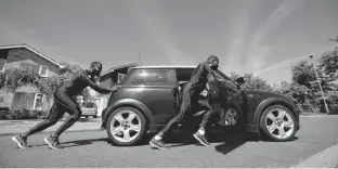  ?? REUTERS • PAUL CHILDS ?? Jamaica Bobsleigh team members Shanwayne Stephens and Nimroy Turgott push a Mini Cooper. They have been pushing the car around the streets of Peterborou­gh as part of their training in Peterborou­gh, Britain.