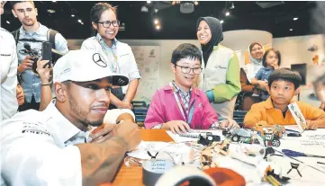  ??  ?? Mercedes AMG Petronas driver Lewis Hamilton meets a group of kids from ‘Faces of Future’ programme during the Mercedes AMG Petronas Team driver meets Malaysian youths at Petrosains in Suria KLCC yesterday. — Bernama photo