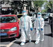  ??  ?? Taking no chances: this couple dressed in full protective suits to take a walk in the streets of Wuhan yesterday