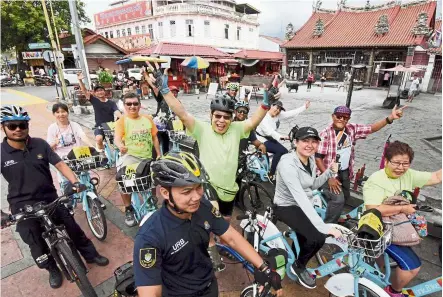  ??  ?? Out and about: Kuan (centre) posing while cycling with his friends as they are being escorted by MBPP enforcemen­t cycling petrol unit led by Zamer (foreground) in front Kuan Yin Teng Temple of Mercy during the Kayuhan Warisan 2020 in George Town, Penang. — MUSTAFA AHMAD/The Star