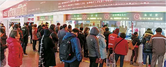  ?? 均 本报见习记者 孟雨涵 摄 ?? 昨天，上海站售票大厅里购买­车票的乘客在等候。因为返程高峰车票开售，售票大厅二楼窗口专门­移至一楼。