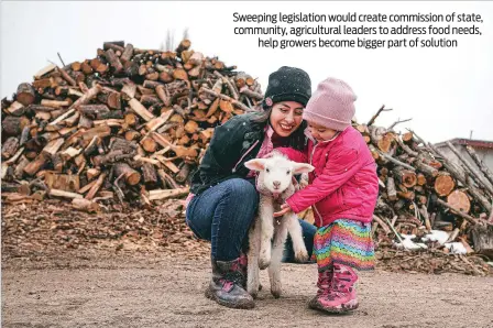  ?? GABRIELA CAMPOS/THE NEW MEXICAN ?? Donne Gonzales and her daughter Lorencita pet Rufus the lamb last month at Chicoyole Farm in Chamisal. Gonzales, 26, supports the Food, Hunger and Farm Act, which calls for the creation of a commission to lay out a plan to reduce hunger in New Mexico and help farmers like her increase their in-state production for residents facing food insecurity.