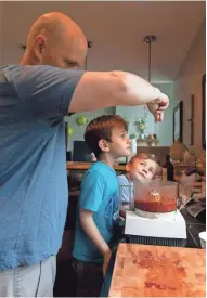  ?? SENTINEL CHRIS KOHLEY, MILWAUKEE JOURNAL ?? Craig Stodola's two sons, Jonas (middle) and Keegan (right) watch their father add ingredient­s to the tomato sauce. "It's a family adventure" Stodola said of why he likes to cook.