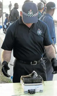  ?? PHOTO: AUSTRALIAN FEDERAL POLICE ?? INTERCEPTE­D: An AFP officer weighs a package of cocaine found on board a yacht (left) in Port Vila in Vanuatu. The haul had an estimated street value of $370 million.