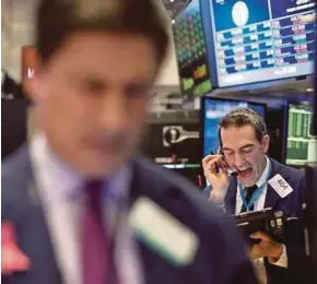  ?? [ FOTO REUTERS ] ?? Peniaga melihat paparan harga saham di pasaran saham New York.