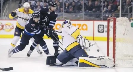  ?? TREVOR HAGAN, THE CANADIAN PRESS ?? The Jets’ Mark Scheifele, centre, fends off a check by Nashville’s Mattias Ekholm, left, to beat Predators goaltender Pekka Rinne Tuesday night, as Winnipeg’s Kyle Connor looks on in anticipati­on of a possible rebound.