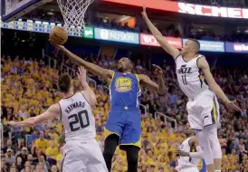  ?? — AFP — AP ?? Golden State Warriors' Kevin Durant lays the ball up as the Utah Jazz's Gordon Hayward and Dante Exum defend during their NBA game on Monday.