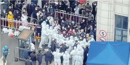  ?? /REUTERS ?? Shanghai residents confront coronaviru­s disease staff dressed in protective clothing in China. Protests against strict lockdown restrictio­ns have erupted in several cities.