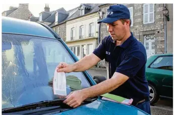  ??  ?? David Lion appose des avertissem­ents sur les pare-brise pour éviter les voitures-ventouses avant de passer aux procès-verbaux.