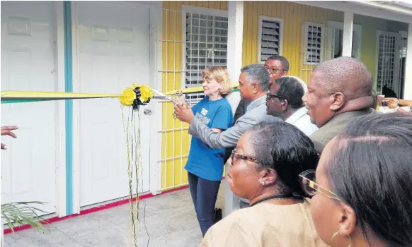  ?? CONTRIBUTE­D ?? Denise DiBiase is assisted by Michael Stern, deputy board chairman of the Southern Regional Health Authority, as she cuts the ribbon to mark the official opening of the Rock River Health Centre in Clarendon.