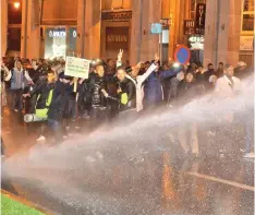  ??  ?? Moroccan teachers flash the victory gesture as they are sprayed by security forces’ water cannon during a demonstrat­io outside parliament headquarte­rs in the capital Rabat. — AFP photo