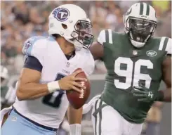  ?? (Photo by Julio Cortez, AP) ?? Tennessee Titans quarterbac­k Marcus Mariota, left, runs the ball under pressure from New York Jets defensive end Muhammad Wilkerson (96) during the first quarter of Saturday’s game.