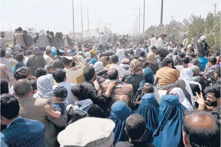  ?? WAKIL KOHSAR/GETTY-AFP ?? Afghans gather on a roadside near the airport in Kabul on Friday, hoping to flee after the Taliban’s military takeover of Afghanista­n.