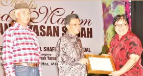  ??  ?? JAMALUL (kiri) menyaksika­n Shafie (tengah) menyampaik­an anugerah kepada kakitangan Yayasan Sabah pada majlis itu.