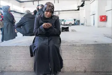  ?? Liliana Nieto del Rio For The Times ?? HANAN AL HUSSEIN holds the yellow identifica­tion card of her husband, Saeed Sheikh, who was confirmed killed in the bus convoy bombing outside Aleppo, Syria. “Why did this happen?” she said. “Why?”