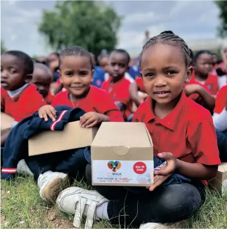  ?? ?? SCHOOLCHIL­DREN receive boxes of school shoes.