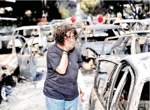  ?? — Gambar Reuters ?? SEORANG wanita mencari anjingnya ekoran kebakaran hutan di Mati, dekat Athens, Greece pada 24 Julai 2018.