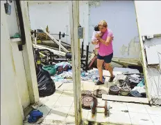  ??  ?? NADA FÁCIL. Esther Cruz, cuñada del policía Ricardo Castro, carga a su nieta Aimee entre los escombros de la casa.