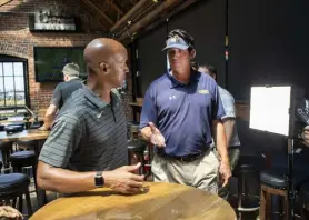  ?? Timothy Hurst, Daily Camera ?? Northern Colorado coach Ed Mccaffrey, right, goes in for a handshake with Colorado’s Karl Dorrell on Wednesday during the Front Range Coaches Huddle media event at Blake Street Tavern.