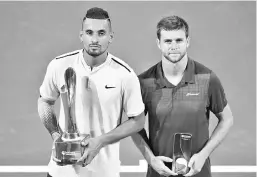  ??  ?? Nick Kyrgios of Australia (L) holds the trophy after beating Ryan Harrison of the US (R) to win the men’s singles final at the Brisbane Internatio­nal tennis tournament at the Pat Rafter Arena in Brisbane on January 7, 2018. - AFP photo