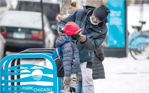  ?? ASHLEE REZIN/SUN-TIMES FILES ?? A man adjusts a boy’s mask as they arrive last month at Jordan Community Public School in Rogers Park.