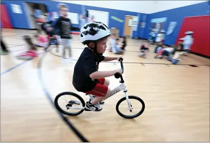  ?? PHOTOS BY JENNY SPARKS — LOVELAND REPORTER-HERALD ?? Centennial Elementary School kindergart­ner Logan Bailey rides a new Strider bike around the gym Thursday with classmates at his school in Loveland. All Kids Bike, a nonprofit teaching kindergart­en students how to ride bikes, brought their program to the school thanks to a donation from Yamaha Corp, USA. Employees of a local bike shop, Tric-city Cycle, assembled the bikes and presented them to the school.