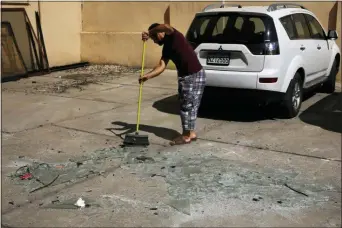  ?? BILAL HUSSEIN — THE ASSOCIATED PRESS ?? A man sweeps broken glass near the 11th-floor building that houses the media office in a stronghold of the Lebanese Hezbollah group, in a southern suburb of Beirut, Lebanon, Sunday.